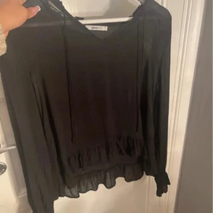 Svart blus med volang från Gina Tricot - Säljer en svart blus från Gina Tricot i storlek XS. Då jag inte längre använder den.
