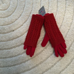 Röda stickade vinterhandskar - Snygga röda handskar med stickad ovandel och slät undersida. Lång modell som går upp över handleden, med ett diskret blommönster på fingertoppen. Perfekta för kalla dagar och ger en cool touch till vinterlooken.