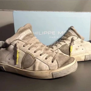 Philippe Model - Snygga Philippe Model sneakers i beige och grå och skinn, med vita snören och coola neongula detaljer. Skorna har en klassisk låg siluett, rund tå och kontrastdetalj i svart på hälen. Perfekta för dig som gillar streetstyle med premiumkänsla.