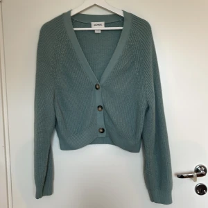 Ljusgrön stickad kofta från Monki XS - Superfin ljusgrön stickad kofta från Monki i storlek XS. Koftan har v-ringning, tre stora knappar framtill och är långärmad. Den är ribbstickad och har en croppad passform.