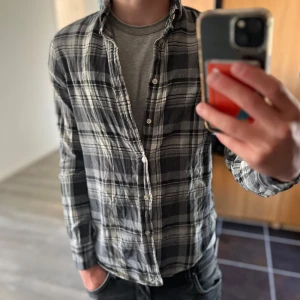 Ralph Lauren skjorta - Snygg rutig skjorta från Ralph Lauren i svart, grått och vitt. Skjortan har klassisk passform, knappar framtill och lång ärm. Tillverkad i mjuk bomull, perfekt för en chill och stilren look. Storlek s men är som xs