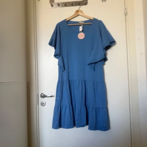 Blå flowy klänning Odd Molly - Superskön blå flowy klänning med volangärmar och rund halsringning. Klänningen har en avslappnad passform och är sydd i flera lager för extra volym. Perfekt för dig som gillar en luftig och chill stil. Från märket Odd Molly i storlek 1 som enligt deras storleksguide motsvarar en storlek S. Mer en M/L. Rymlig i storlek. Helt ny med tags. 