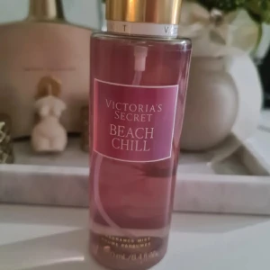 Victoria's Secret Beach Chill mist - Fräsch body mist från Victoria's Secret i doften Beach Chill. Flaskan är genomskinlig med rosa vätska och har ett guldigt lock. Doften har inslag av krispigt päron, liljekonvalj och glittrande vatten. Rymmer 250 ml och är perfekt för dig som gillar fruktiga och blommiga toner. Helt ny och oanvänd. Förhandlar ej