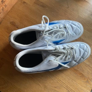 Vita Mizuno fotbollsskor strl 44 - Helt oanvända var försmå när jag köpte dem endast testade aldrig använda extra breda med väldigt skön passform pris kan diskuteras vid snabba affär 💗⚽️.                                                                                   Snygga vita fotbollsskor från Mizuno med blå detalj på sidan. Ovandelen är quiltad och har snörning för bra passform. Skorna är tillverkade i syntet och mesh för bra andningsförmåga och komfort. Perfekta för dig som vill sticka ut på planen.