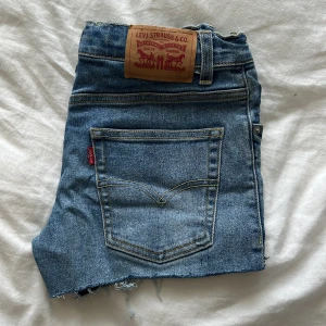 Levi's jeansshorts  - Snygga blå jeansshorts från Levi's i loose taper-modell. fransiga benslut samt slitna detaljer framtill. Perfekta för sommardagar och festivaler.