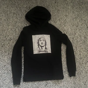 Svart Limitato hoodie med tryck - Svart hoodie från Limitato med ett tryck på Sylvester Stallone💪. Tröjan har huva, långa ärmar och en klassisk passform. Perfekt för dig som gillar streetwear och stilrena detaljer. 