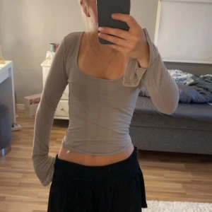 Beige långärmad topp Gina Tricot - Säljer en beige långärmad topp från Gina Tricot med snygg, djup rundad urringning. Modellen är tight och sitter figurnära, perfekt att styla med både jeans och kjol. Mjuk och stretchig bomullskänsla som gör den superbekväm.