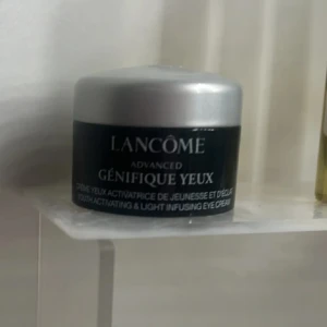 Lancôme Génifique Yeux ögonkräm - Lancôme Advanced Génifique Yeux är en ögonkräm i en svart och silver burk. Krämen är vit och har en lätt, gel-liknande konsistens. Perfekt för dig som vill boosta huden runt ögonen med fukt och lyster.använd men mycket kvar se bild 