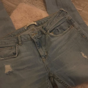 Ljusblå ripped jeans från g perfect jeans - Säljer ett par ljusblå jeans från g perfect jeans, modellen KRISTEN. Jeansen har flera slitningar och hål på benen för en riktigt trendig, avslappnad look. Klassisk femficksmodell med dragkedja och knapp. Perfekta för dig som gillar streetstyle.