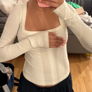 Vit ribbad långärmad topp - Säljer en vit långärmad topp med fyrkantig ringning och ribbad struktur. Toppen är figurnära och har långa ärmar med lite extra längd. Perfekt för dig som gillar en clean och stilren look. Superenkel att matcha med både jeans och kjol. oppsss de e svarta skuggor som syns på bilderna pågrund av ljuset!!
