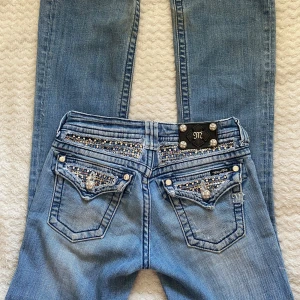 Miss Me ljusblå jeans med paljettdetaljer - säljer ett par supersnygga lågmidjade Miss Me jeans i väldigt fint skick då de är för små på mig, de har några väldigt små fläckar som syns på sista bilden. Jag skulle säga att jeansen är små i storlek! Midjemåttet är 70 cm i omkrets och innerbenslängden är 82 cm. 