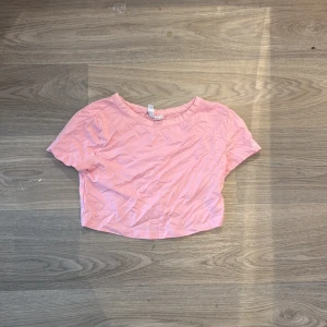 Ljusrosa croppad topp från H&M - En ljusrosa croppad topp från H&M Basic med rund halsringning och korta ärmar. Tillverkad i mjuk bomull, perfekt för en chill och avslappnad stil. Enkel design som är lätt att matcha med jeans eller kjol.