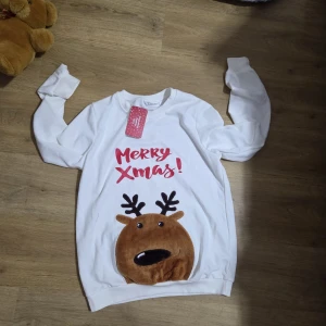Vit jultröja med renmotiv från Patpat - Vit långärmad tröja från Patpat med rött tryck 'Merry Xmas!' och en gullig brun plysch-ren med svarta horn framtill. Perfekt för julmys och selfies. Mjuk och skön bomullskänsla, normal passform och rund hals.