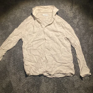 Beige linneskjorta Mango - Snygg och luftig beige skjorta från Mango i 100% linne. Skjortan har klassisk krage, knäppning framtill och långa ärmar. Den är prefekt för varma sommar dagar och är riktigt stilren 🙌 Hör av dig vid eventuella frågor mvh //Ruben