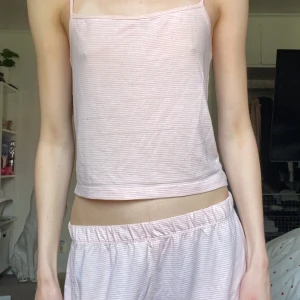 Rosa set - Supersöt ljusrosa linnetopp med tunna axelband och smala vita ränder, & shorts!Toppen är croppad och har en enkel, rak passform. Perfekt för varma dagar eller som pyjamas. Mjuk och skön i bomullsmaterial😻Se sista bilden för en fläck på toppen! Använd några gånger, toppen är i sämre skick än shortsen🙌🏻