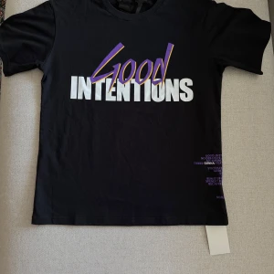 Svart Vlone Good Intentions t-shirt - Svart t-shirt från Vlone med stor vit och lila 'Good Intentions'-text på framsidan och en stor lila V med duvor på ryggen. Perfekt för sommar fits, har den även i vit, storlek S