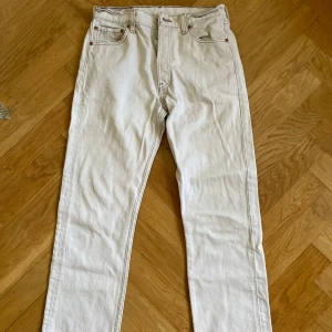 Levi's 501 vita jeans 30/30 - Säljer ett par klassiska vita Levi's 501 jeans i rak modell. Byxorna har fem fickor, knappgylf och snygga kontrastsömmar. Perfekta för dig som vill ha en clean och tidlös look. Materialet är kraftig denim i bomull. Litet slitage mellan benen. 