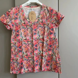 Färgglad paisleymönstrad t-shirt Lo-ika - Superfin t-shirt från Lo-ika med färgstarkt paisleymönster i rosa, blått, grönt och orange. Modellen är kortärmad med v-ringning och tillverkad i mjuk bomull. Perfekt för dig som gillar unika och färgglada plagg som sticker ut.