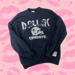Dallas Cowboys sweatshirt Nutmeg XL - Mörkblå vintage Dallas Cowboys NFL sweatshirt från Nutmeg Mills i storlek XL med Dallas Cowboys-tryck och hjälm på bröstet. Tröjan har rund hals, långa ärmar och breda muddar. Perfekt för dig som gillar amerikansk fotboll och sportig streetstyle. 50% bomull 50% polyester. Importerad från USA. 