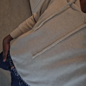 Beige stickad hoodie med luva - Säljer en beige stickad hoodie med huva och snörning. Tröjan har lång ärm och en avslappnad passform, perfekt att slänga på sig till jeans. Enkel och stilren design som funkar till många olika looks. 