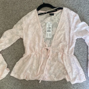 Ljusrosa blommig blus med knyt XS - Jättefin knyt blus från Gina tricot. Säljer eftersom den aldrig kom till användning.