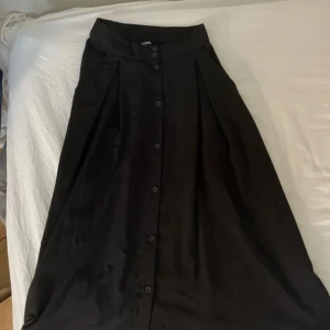 Svart långkjol med knappar  - Svart långkjol från Monki med knappar hela vägen framtill. Använd ett par gånger 