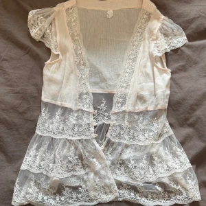 Ljus rosa spetsblus med volanger - Romantisk ljus rosa blus med transparent spets.😍 Knappar framtill och flera lager volanger nedtill. Perfekt för dig som gillar en söt och bohemisk stil. Passar mig med S!❤️