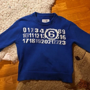 Blå stickad tröja från Maison Margiela - PRIS GÅR ATT DISKUTERAS OM! Blå stickad tröja från Maison Margiela med vit grafisk print av siffror och en stor sexa på bröstet. Tröjan har rund hals, ribbade muddar och lång ärm. Säljer tröjan för att jag växt ut den. QR Kod finns på ”tagen” som satt fast i tröjan som leder till Maison Margiela hemsidan! Kommer med orginal paketet och tagen såklart 😁Svarar på alla frågor! 