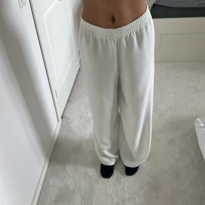 Vita wide mjukisbyxor från Zara XS - Säljer ett par vita mjukisbyxor från Zara i storlek XS. Byxorna har bred resår i midjan, är riktigt vida i modellen och har en skön loose fit. Perfekta för chill dagar eller när du vill ha något bekvämt men ändå snyggt på dig.