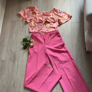  ( om man vill ha enskilda säg till!)Vida rosa kostymbyxor med en snygg cool tröja - Snygga kostymbyxor i en stark rosa färg med vida ben och mid waist. Byxorna har klassisk knapp och dragkedja framtill samt hällor för bälte. Perfekta för dig som vill sticka ut med färg och stil.