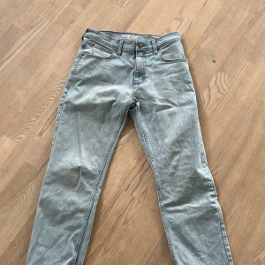 Ljusblå straight jeans från Wrangler - Säljer ett par ljusblå jeans från Wrangler i rak modell. Klassisk femficksdesign, normal passform och snygga detaljer på bakfickorna. Tillverkade i bomull och perfekta för dig som gillar en enkel och clean look.