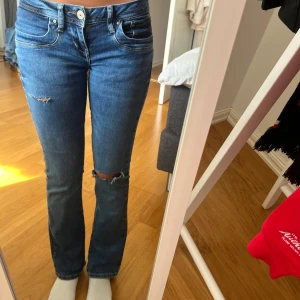 Blå slitna bootcut jeans från LTB - Säljer ett par blå jeans från LTB i modellen valerie med bootcut stil och snygga slitningar på knä och lår. Slitningarna var där sen innan när jag köpte de av en annan person på appen, har själv knappt använt de💕💕