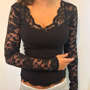 Svart spetsblus med lång ärm - Supersnygg spetstopp som är perfekt till fest. Jag har själv sytt på den nedre spetsen och rosetten samt sytt in den. Passar både S och XS. Diskuterar gärna pris! 
