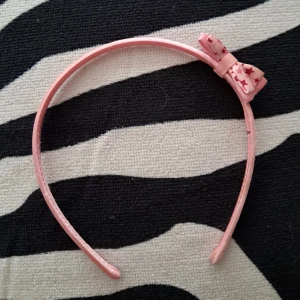 Rosa diadem med rosett och stjärnor - Sött rosa diadem med en liten rosett på sidan, dekorerad med stjärnmönster. Fint skick:)