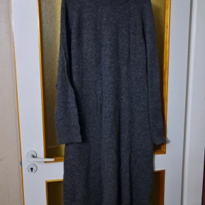 Mörkgrå stickad långklänning - Mysig mörkgrå stickad långklänning med lång ärm och enkel design. Klänningen är i ett mjukt och värmande material. Väldigt skön :)