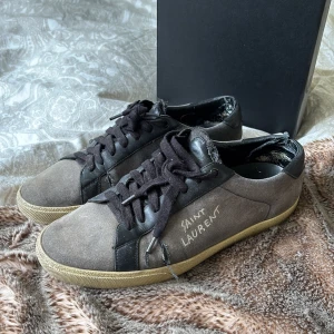 Saint Laurent skor - Ovanlig modell av Saint Laurent skor i storlek 42 1/2 (passar även ofta 43). Modellen är SL/06 (tror jag). Inga defekter annat än att det är en liten skada på vänster häl. Den är halv fixad men går att enkelt fixa. Säljer pga att de är för små för mig. Går att kombinera med många olika plagg pga deras färg.