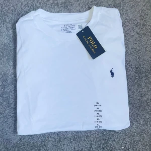 Vit t-shirt från Polo Ralph Lauren  - Vit klassisk t-shirt från Polo Ralph Lauren i storlek xl i barn storlek vilket motsvarar st 170. Tillverkad i mjuk bomull för en skön och clean look.