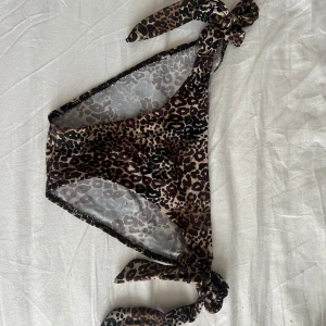 Leopardmönstrad bikiniunderdel med knyt - Snygg bikiniunderdel med leopardmönster i bruna och svarta toner. Modellen har trendiga knytband på sidorna som gör att du kan justera passformen.