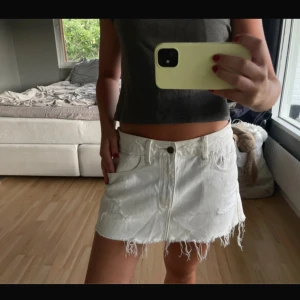 Vit jeanskjol med fransig kant - Säljer en vit kort jeanskjol med fransig nederkant och slitna detaljer. Andvänd endas 1 gång, stoleken är w28 men passar mig som bär stolek S!
