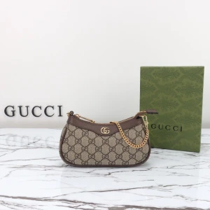 Gucci Ophidia väska - Snygg axelväska från Gucci i beige och brunt med klassiskt GG-mönster. Väskan har guldfärgad kedja, dragkedja upptill och detaljer i brunt skinn. Perfekt storlek för det viktigaste och en ikonisk accessoar för din look.