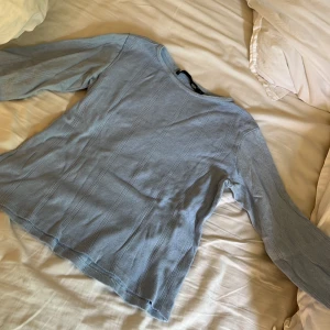 Ljusblå stickad tröja från 157 - Supersöt ljusblå stickad tröja från 157 med diskret mönsterstickning och rund hals. Långärmad och i mjukt material som känns skönt mot huden. Perfekt att styla med jeans eller kjol för en chill look.