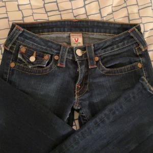 True Religion jeans - Mörkblå lågmidjade jeans från True Religion i storlek 26, modell Billy med en snygg tvätt. Lite nötta längst ner på benen som man ser i bild nummer 2 men annars inga skador! Pris kan självklart diskuteras❤️