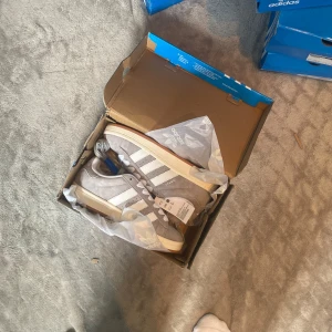Adidas Campus grå sneakers i mocka - 𝗔𝗱𝗶𝗱𝗮𝘀 𝗖𝗮𝗺𝗽𝘂𝘀 00 – 𝗴𝗿å, 𝘀𝘁𝗿𝗹 38 Helt nya och oanvända sneakers. Boxen är delvis skadad då de köpts upp från ett lager, därför säljs de billigare. Skorna är i perfekt skick.
