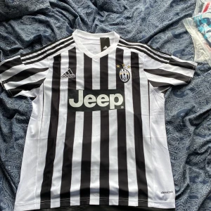Juventus Pogba 10 Adidas tröja L - Juventus matchtröja från Adidas med Pogba 10 på ryggen. Klassisk svartvit randig design, Juventus-emblem med tre stjärnor på bröstet och Jeep som sponsor. Tillverkad i lätt och ventilerande climacool-material, perfekt för fotbollsälskare. Storleken är L så passar någon som är 175-180 cm lång. Vid minsta fundering eller om du vill ha mer bilder på tröjan hör av dig.