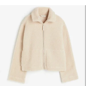 Beige teddyjacka med dragkedja - Supermjuk och fluffig beige teddyjacka med dragkedja framtill och stora fickor. Jackan har en avslappnad passform och hög krage som håller dig varm. Perfekt för kyliga dagar när du vill vara både bekväm och snygg.