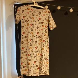 Harry Potter klänning Reserved - Supergullig Harry Potter-klänning från Reserved med kort ärm och rund hals. Ljusgrå botten med färgglada tryck av karaktärer från Harry Potter över hela klänningen. Perfekt för dig som älskar magi och vill sticka ut med en unik look!