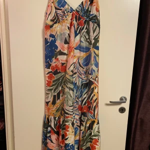 H&M flerfärgad klänning, storlek S - Färgglad maxiklänning med blommigt mönster och smala axelband. Klänningen har en v-ringning och en rynkad detalj nedtill. Superfin sommarklänning, både till vardags och fest! 