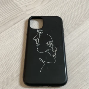 Svart mobilskal med konstnärligt motiv - Snyggt svart mobilskal med ett stilrent, konstnärligt motiv av två ansikten i vit linje. Perfekt för att ge din mobil en unik och modern look. Skalet är gjort av ett slitstarkt material som skyddar mot repor och stötar. Pris kan diskuteras och hör av er vid frågor!!!❤️‍🔥❤️‍🔥🙌🏼🙌🏼