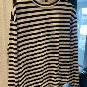 Randig långärmad tröja från Pull&Bear - Säljer en  randig tröja från Pull&Bear i marinblått och vitt. Tröjan har långa ärmar och är perfekt för en avslappnad stil. Mjukt material.