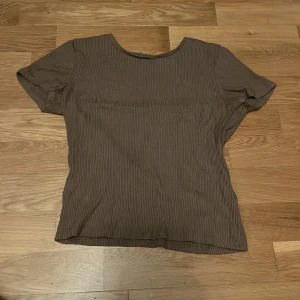 Brun ribbad topp från Lindex - Säljer en brun ribbad topp från Lindex i storlek S. Toppen har korta ärmar och en rund halsringning. Perfekt för en stilren och bekväm look.